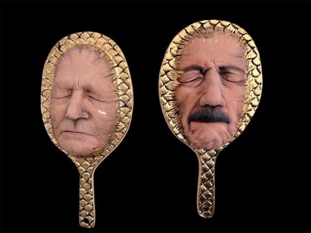 Reflections, a pair of ceramic wall masks by Ireri Krueger set into gilded hand-mirror frames, each holding a sculpted human face