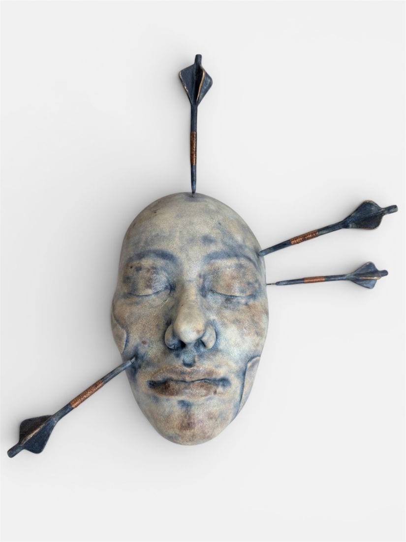 Saint Sebastian, a ceramic wall mask by Ireri Krueger of a serene blue-toned face pierced by three arrows