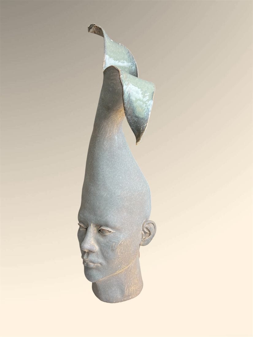 Unfurling, a tall ceramic sculpture by Ireri Krueger of an elongated grey head with two glossy leaf-like forms opening from the crown